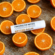 American Made Better Balm surrounded by sliced oranges on a wooden surface