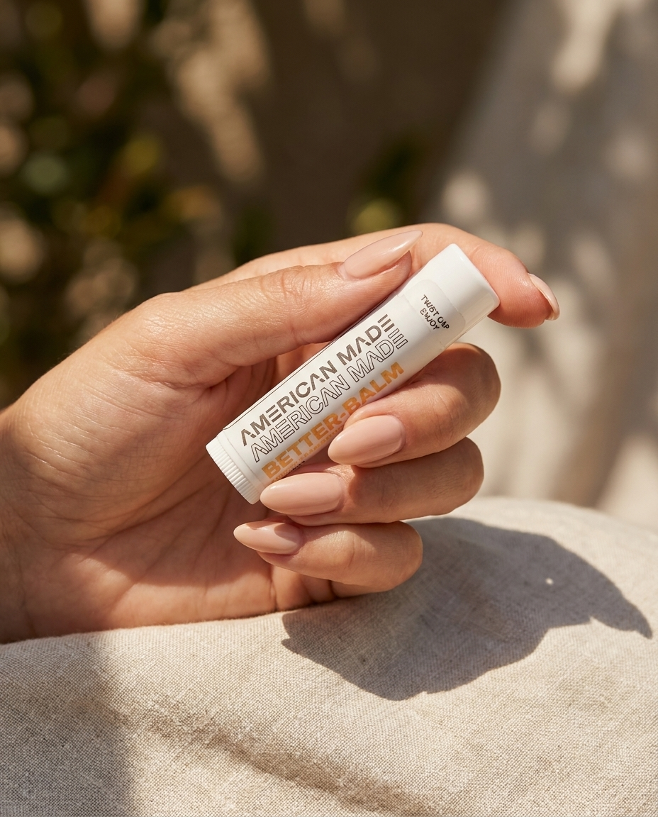 Hand holding a tube of 'American Made' lip balm against a natural background