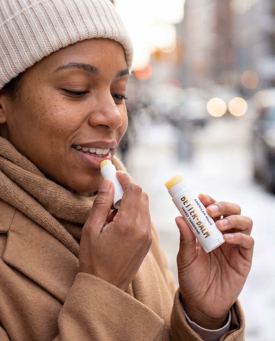 Woman applying BetterBalm lip balm outdoors on a winter morning